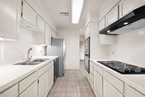 A fully appointed, pristine kitchen with abundant storage, solid surface counters, built-in oven and microwave, and walk-in pantry