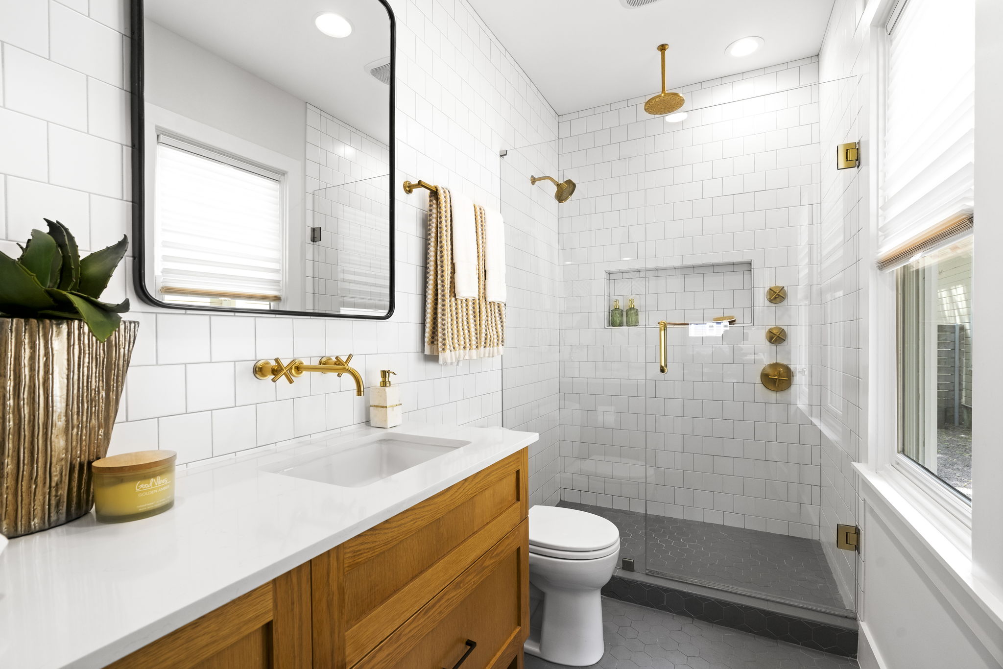 The en suite bathroom dazzles with Brass Brushed Gold bathroom hardware, floor-to-ceiling white subway tile, dual shower heads with rain feature and luxurious quartz countertops.