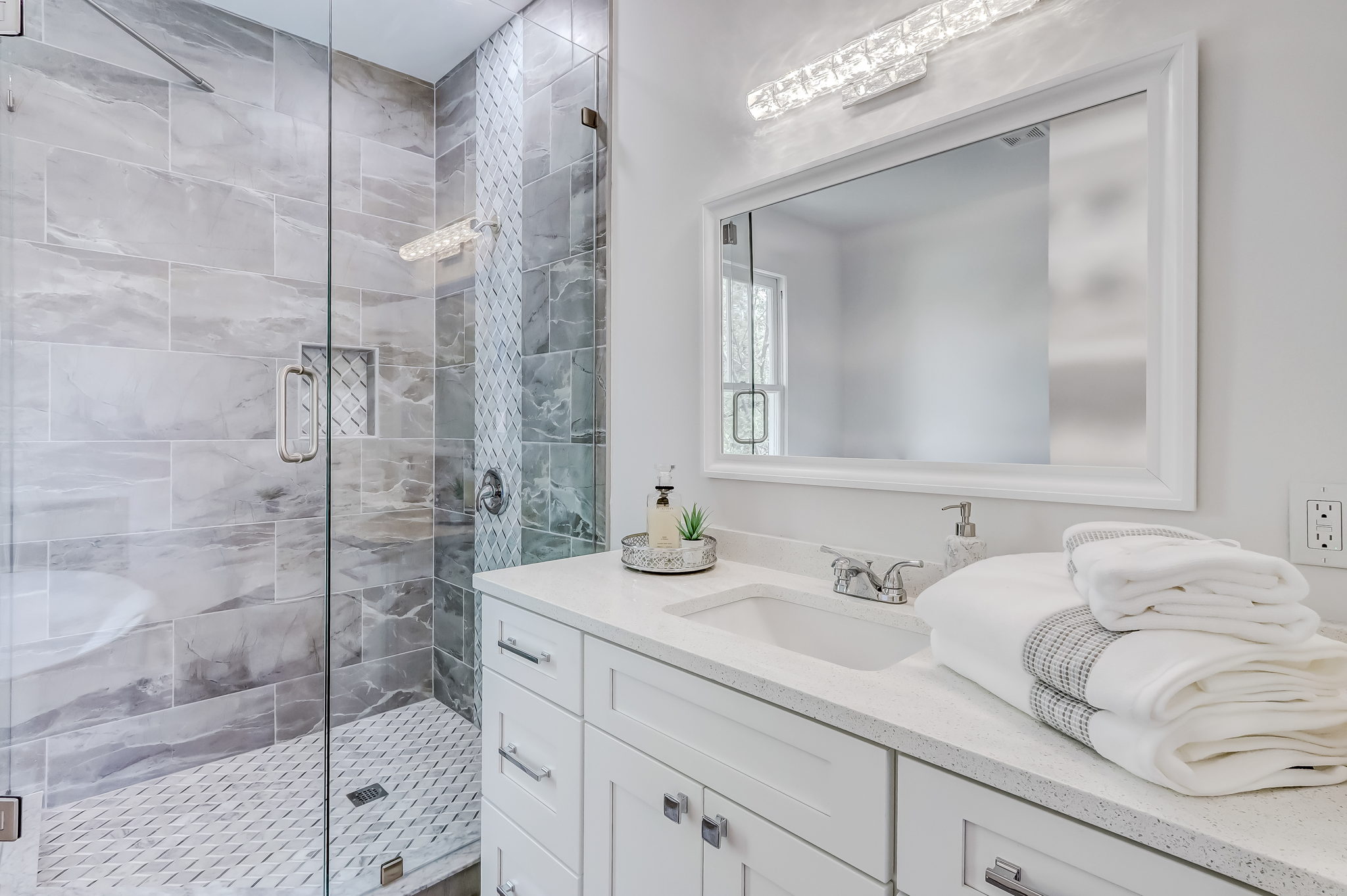 Master bath features fine finishes with wall-to-ceiling tiled shower and frameless glass door