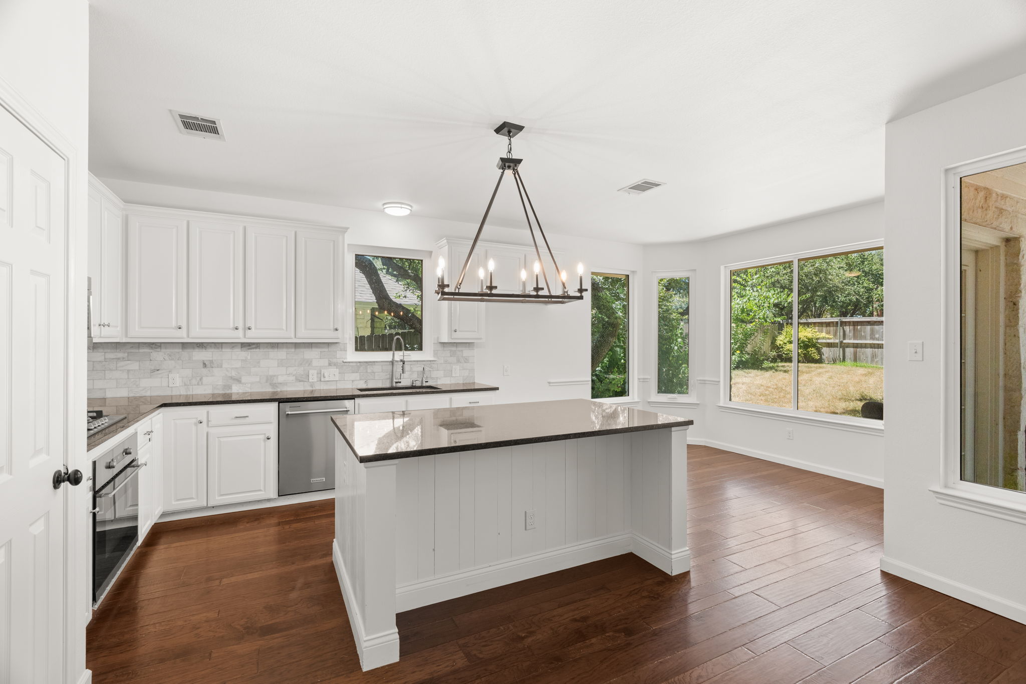 At the heart of the home, the light-filled, well-appointed kitchen boasts a center island, gas cooktop, ample cabinetry and a cozy dining nook overlooking the lush backyard.