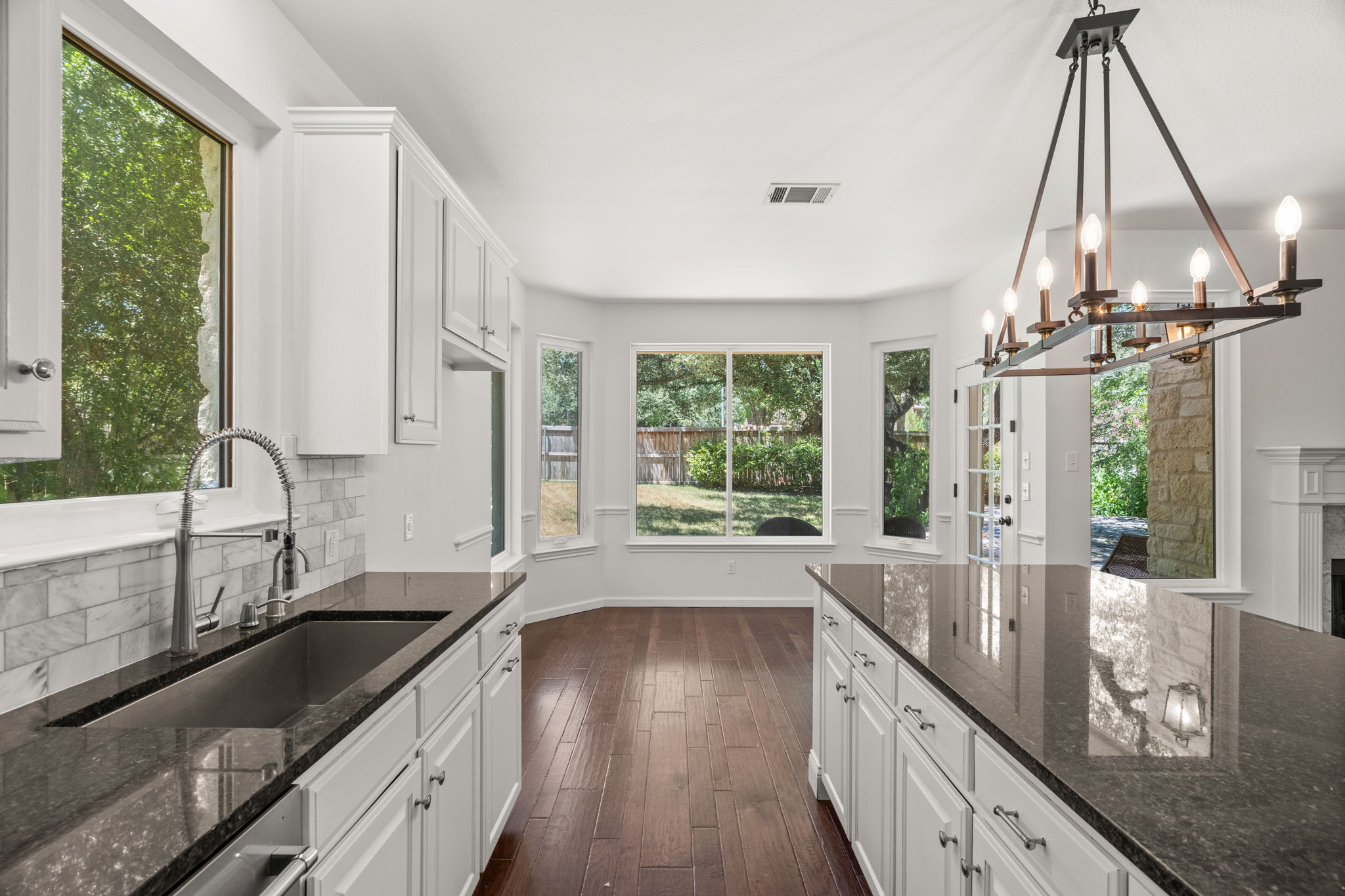 At the heart of the home, the light-filled, well-appointed kitchen boasts a center island, gas cooktop, ample cabinetry and a cozy dining nook overlooking the lush backyard.