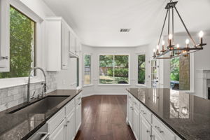 At the heart of the home, the light-filled, well-appointed kitchen boasts a center island, gas cooktop, ample cabinetry and a cozy dining nook overlooking the lush backyard.
