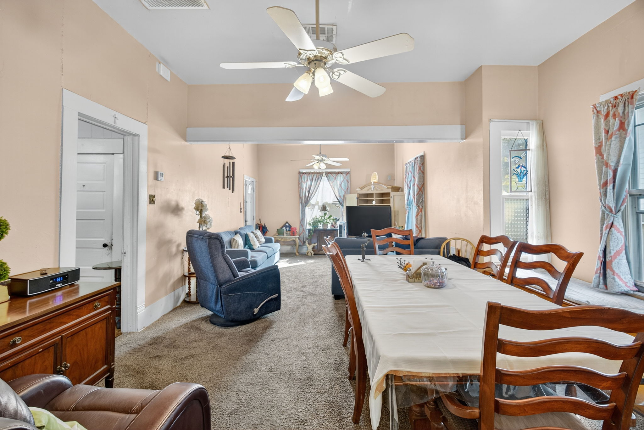 Another view of the dining room and living room each with their own ceiling fans.