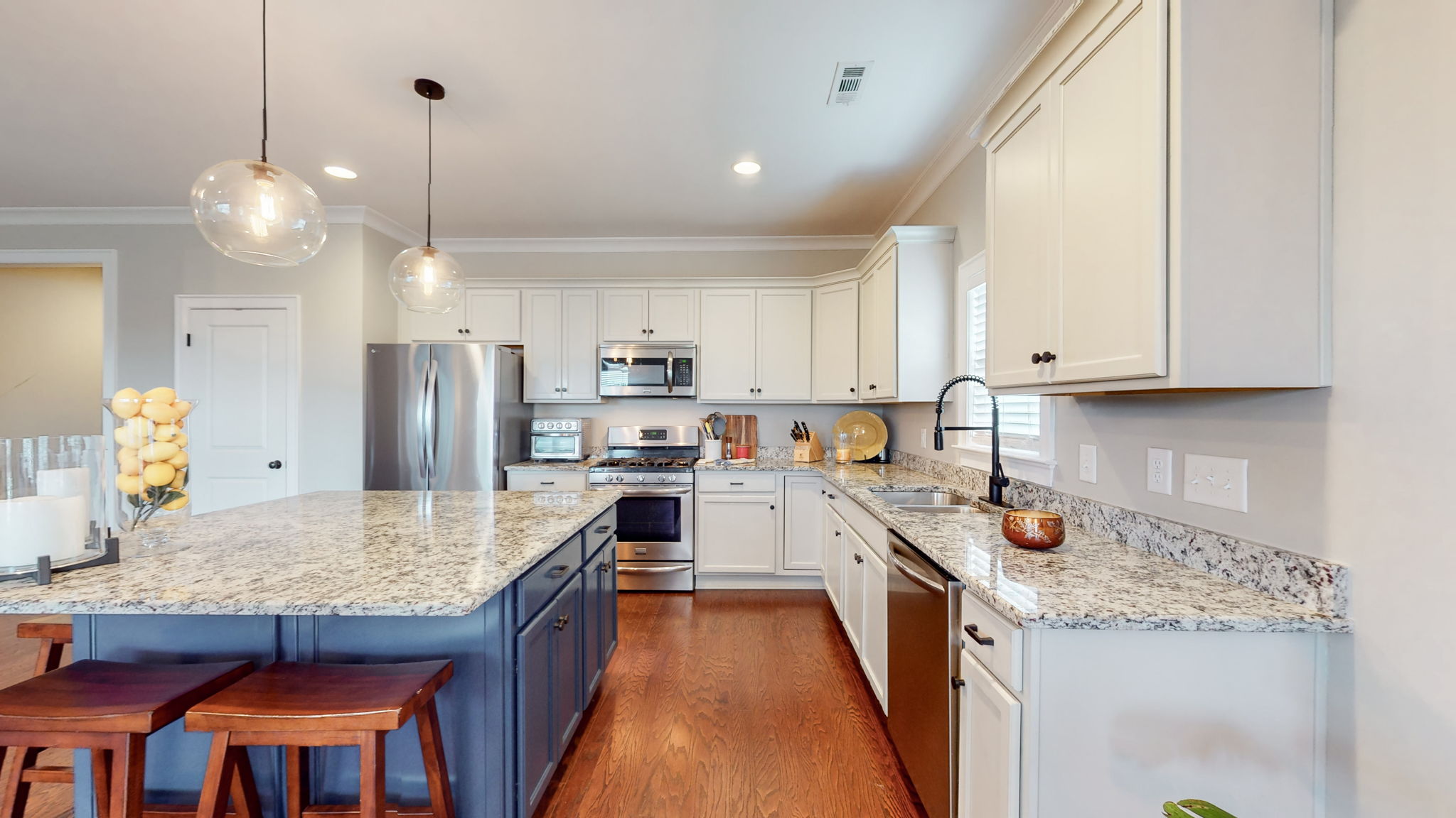 The spacious kitchen with extra large island has ample storage, granite countertops, stainless appliances, and a custom pantry organizer.