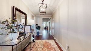 The welcoming entryway features a custom light fixture, hardwood floors throughout, and ample room for an entry table.