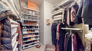 This custom Elfa closet features clothing racks of all lengths, a shoe wall, and shelving for additional storage.