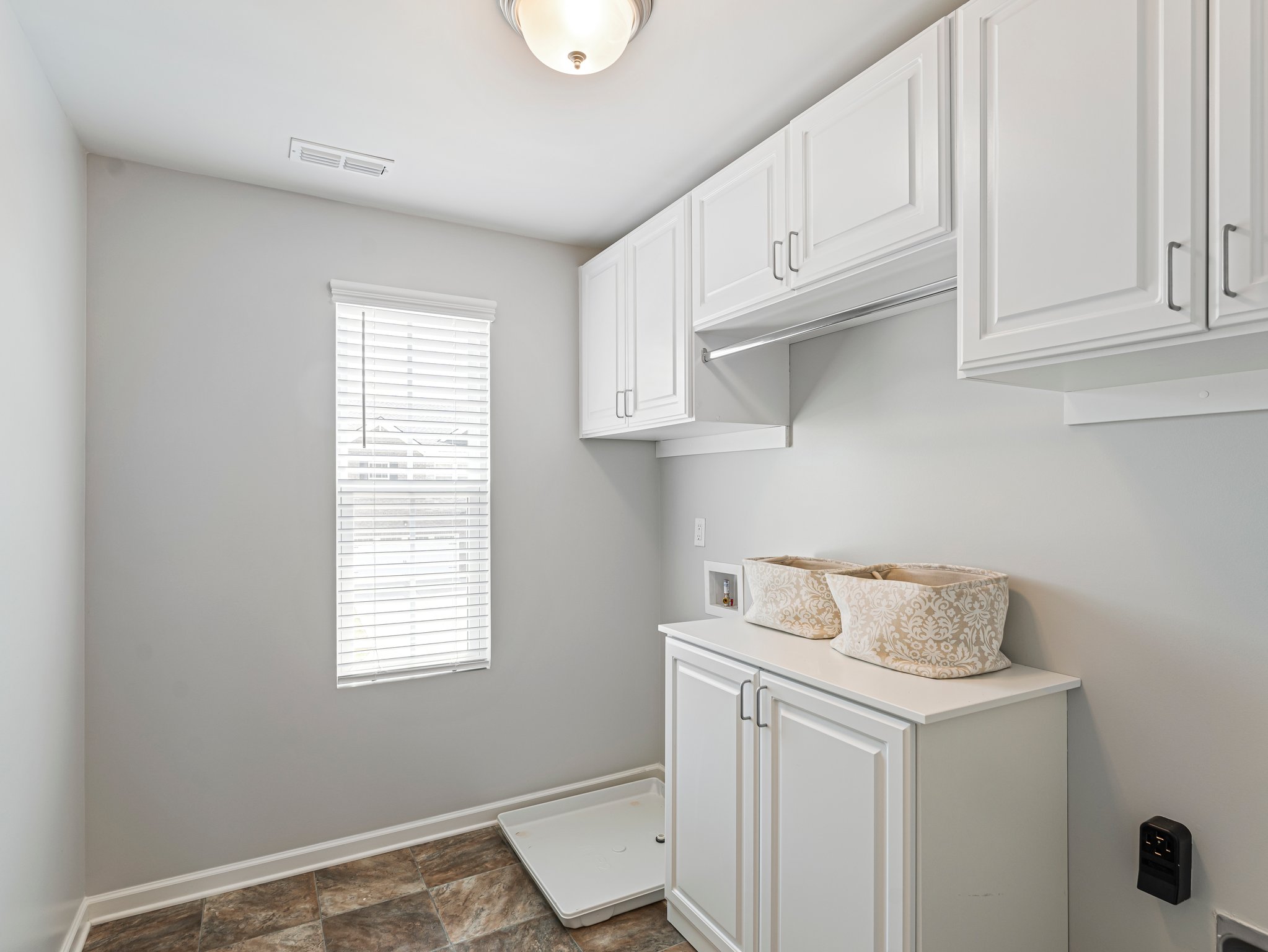 Large upstairs laundry room with custom cabinetry and a window overlooking the front yard