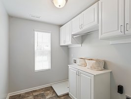 Large upstairs laundry room with custom cabinetry and a window overlooking the front yard