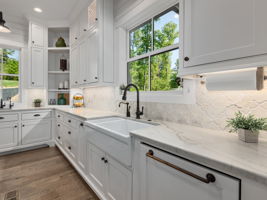 Spacious quartzite counters and farm house sink lead into tucked away wet pantry
