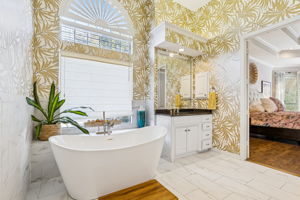 Great view of freestanding tub and primary bedroom