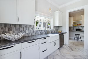 A coordinated tile backsplash complements the gray and white color scheme of the kitchen