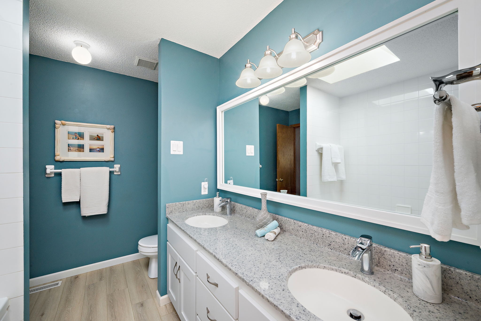 Upper level bath with dual hard surface vanity, framed mirror and LVT flooring