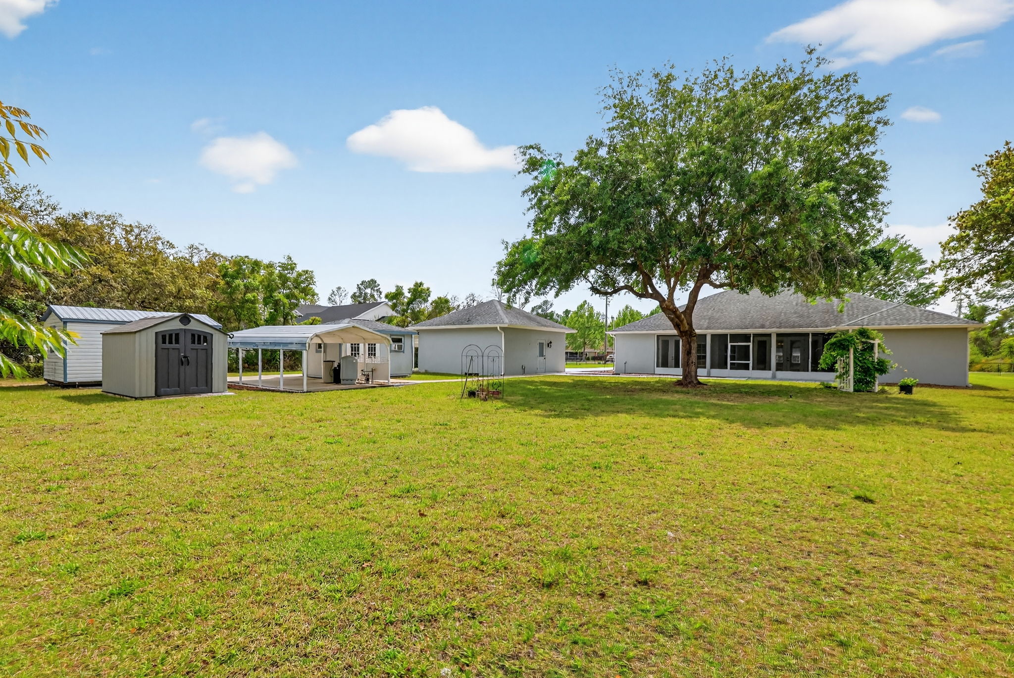Rear Elevation with Garage, Three Sheds, and One of the Carports