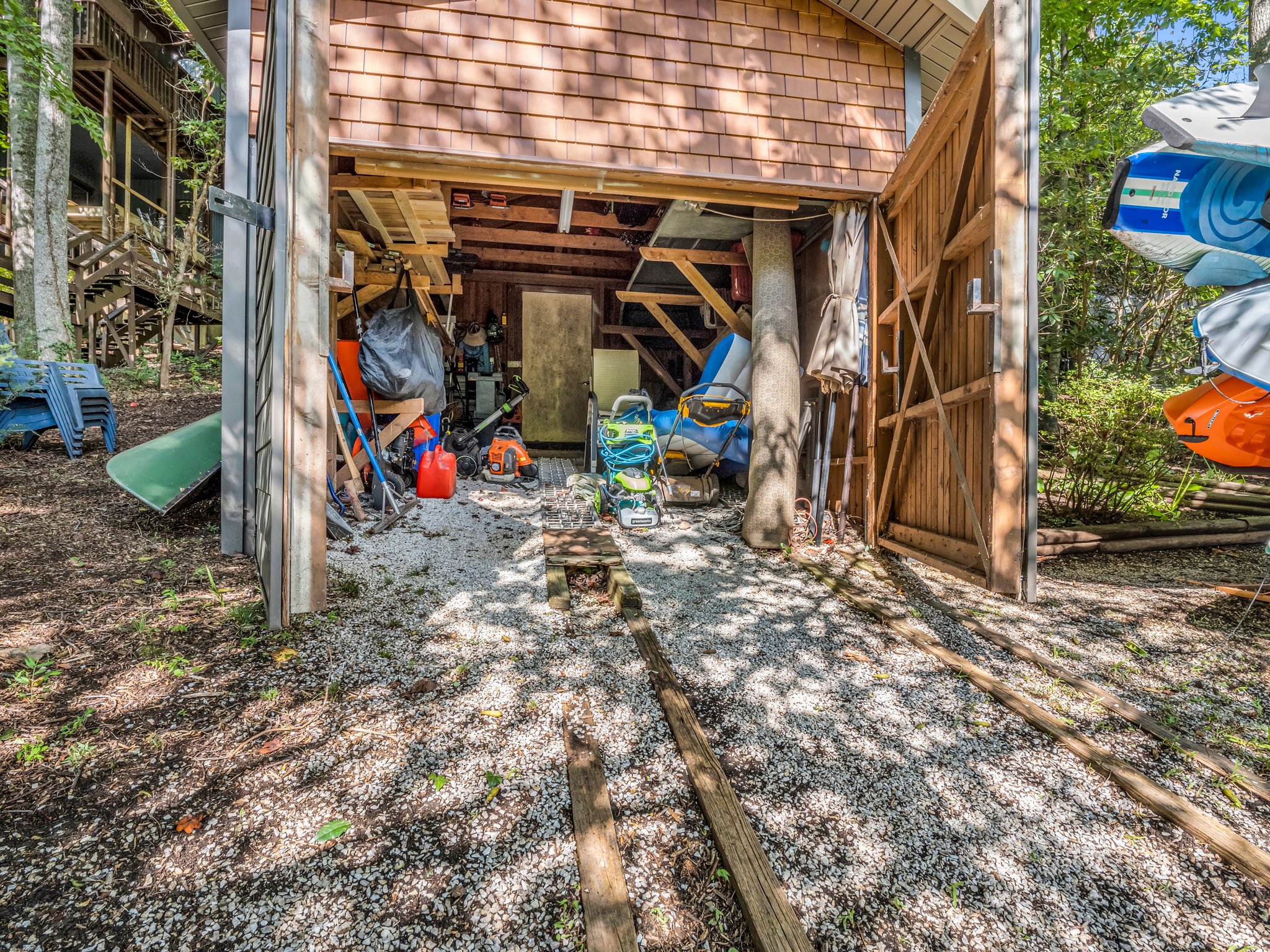 Boathouse with track ramp for easy launch and boat storage offers space for water toys and gear.