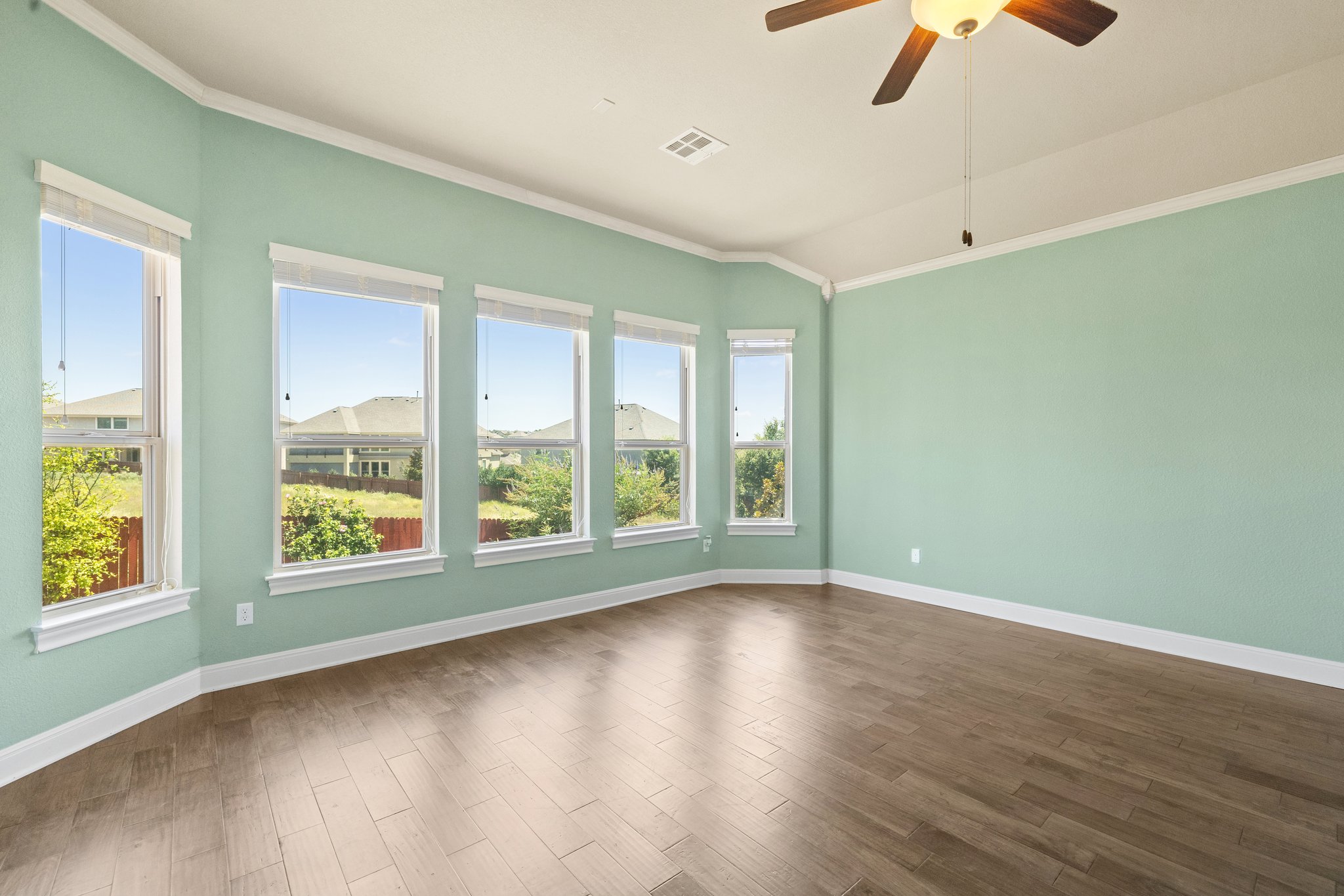 The primary bedroom has a wall of windows overlooking the back yard and green space behind it.