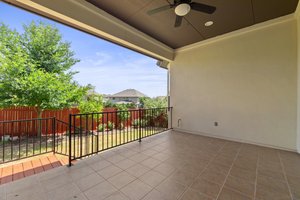 The spacious, covered back patio looks out into the green space behind the house.