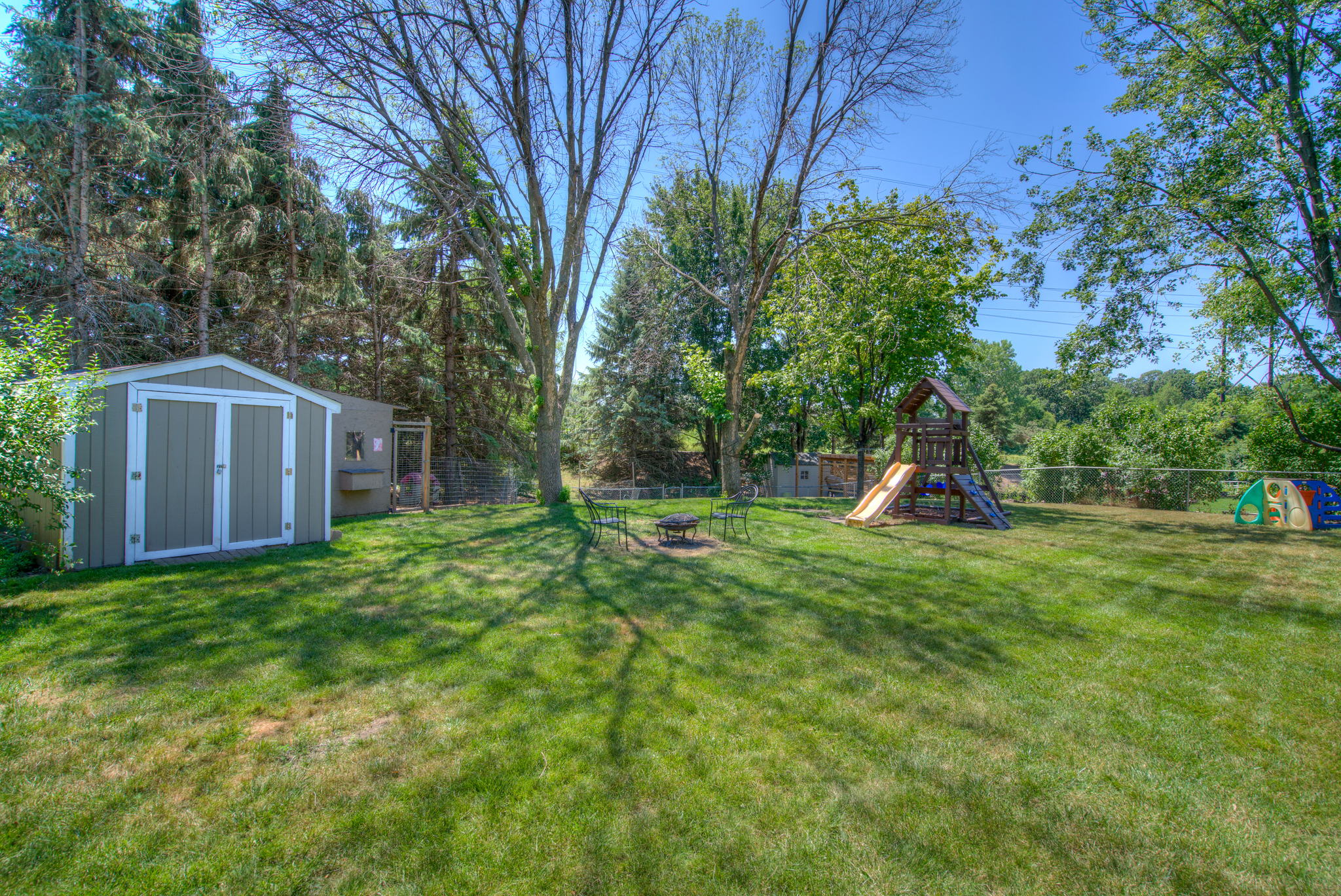 The fenced back yard includes a large storage shed and play set.