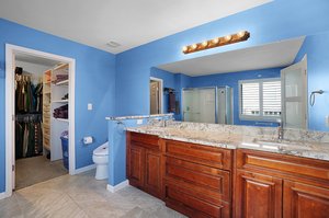 En-suite with granite countertops, double sink, and walk in closet