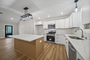 Kitchen with quartz countertops, tile backsplash, custom cabinets, recessed lighting and stainless steel appliances