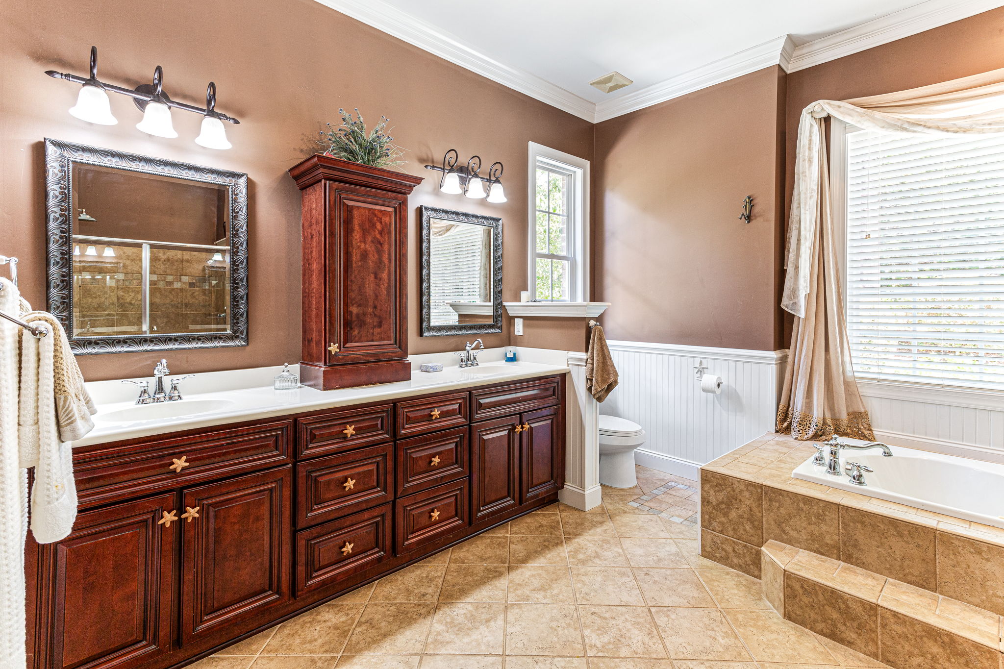 Master bathroom with custom-built cabinets, chair rail wainscoting, double sink vanity, alcove jetted tub.