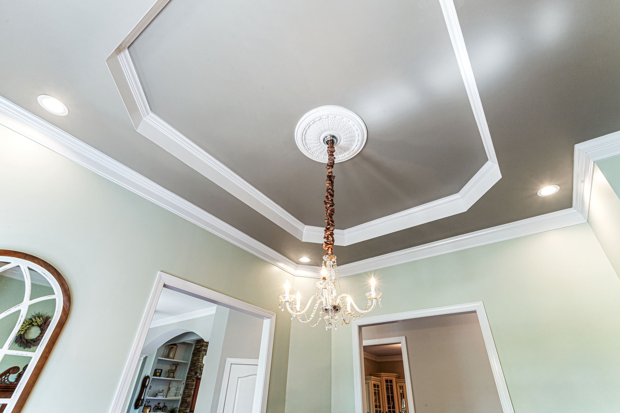 12-foot tray ceiling enhanced by step-out crown molding and subtle backlighting, crowned with a Swarovski Crystal Chandelier.