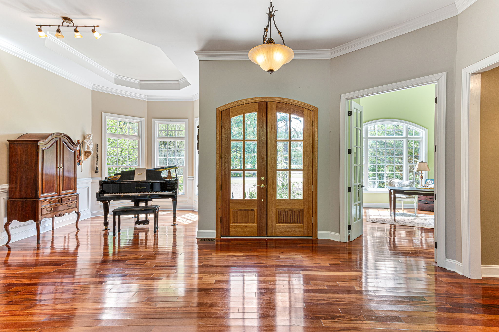Piano room with tray ceiling and chair rail wainscoting throughout.
