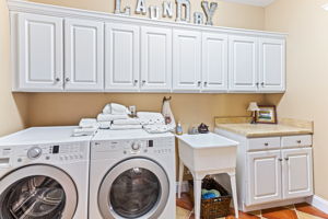 Laundry with utility sink, cabinets and Ballard Designs built-in hanging rack.