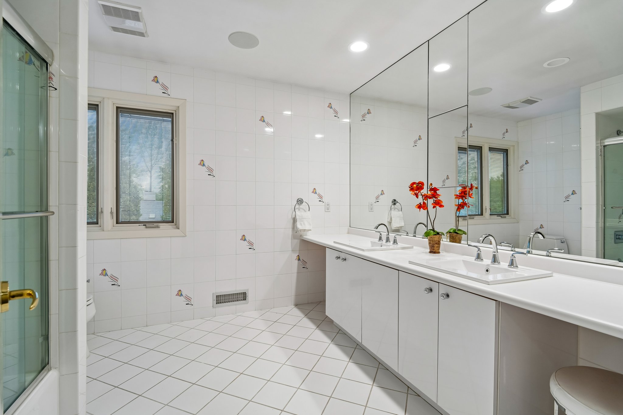 Second of two second floor oversized hall baths is designed for effortless mornings, featuring dual-sinks, custom cabinetry and dedicated make-up vanity. Wrapped in walls of mirrors that enhance the room's light and scale, this space is completed by a classic tub-over shower for ultimate versatility.