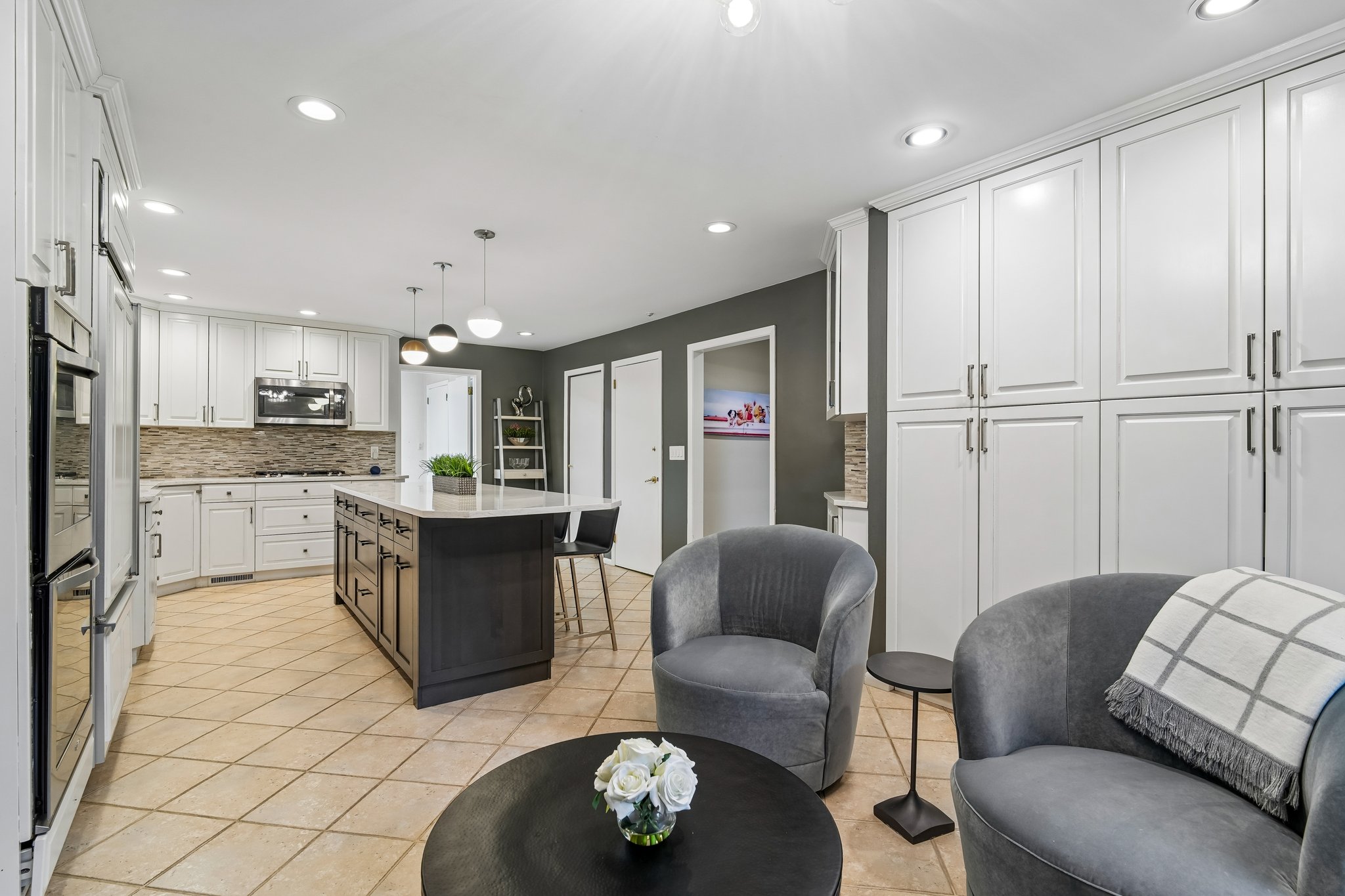 This alternative view reveals the true scale of the kitchen storage capacity. The bright breakfast area, currently styled with a cocktail table and chairs, easily accommodates a full-sized dining table for gatherings.