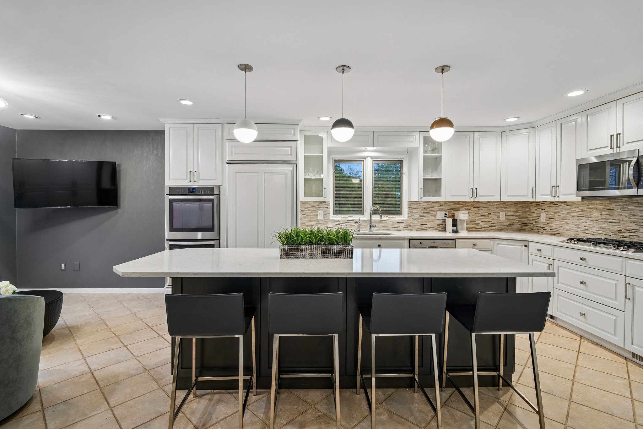The heart of the home is a designer kitchen, featuring an oversized center island with seating that serves as the ultimate hub for daily life. From casual morning coffee to large scale holiday prep, the expansive workspace is perfectly positioned for both functionality and social connection.