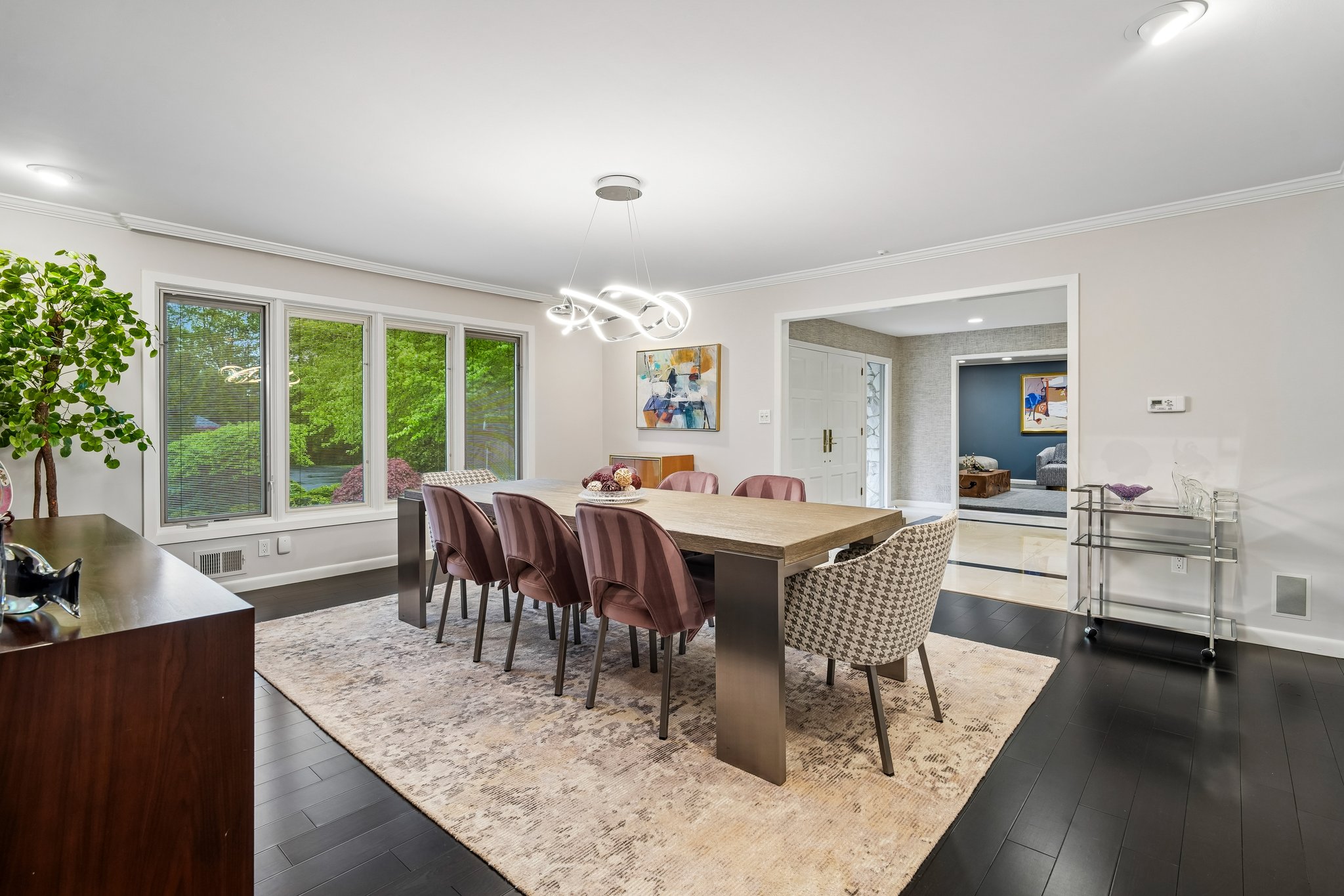 Walls of windows frame this formal dining room, blending outdoor beauty with indoor elegance.