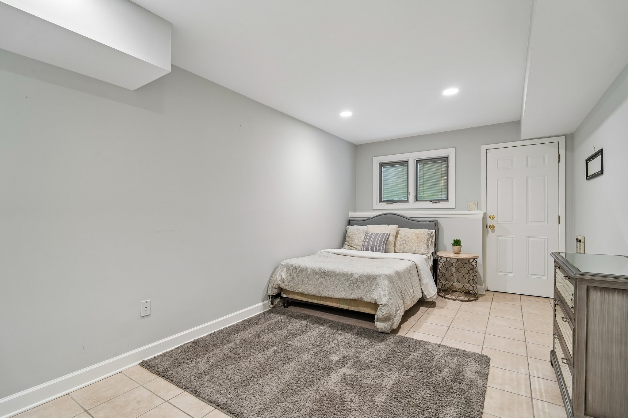 The lower level features a secluded fifth bedroom, perfect for guest or multi-family generational living. This bright and spacious suite offer a private door for direct access, ensuring independence and comfort in a quiet corner of the home.