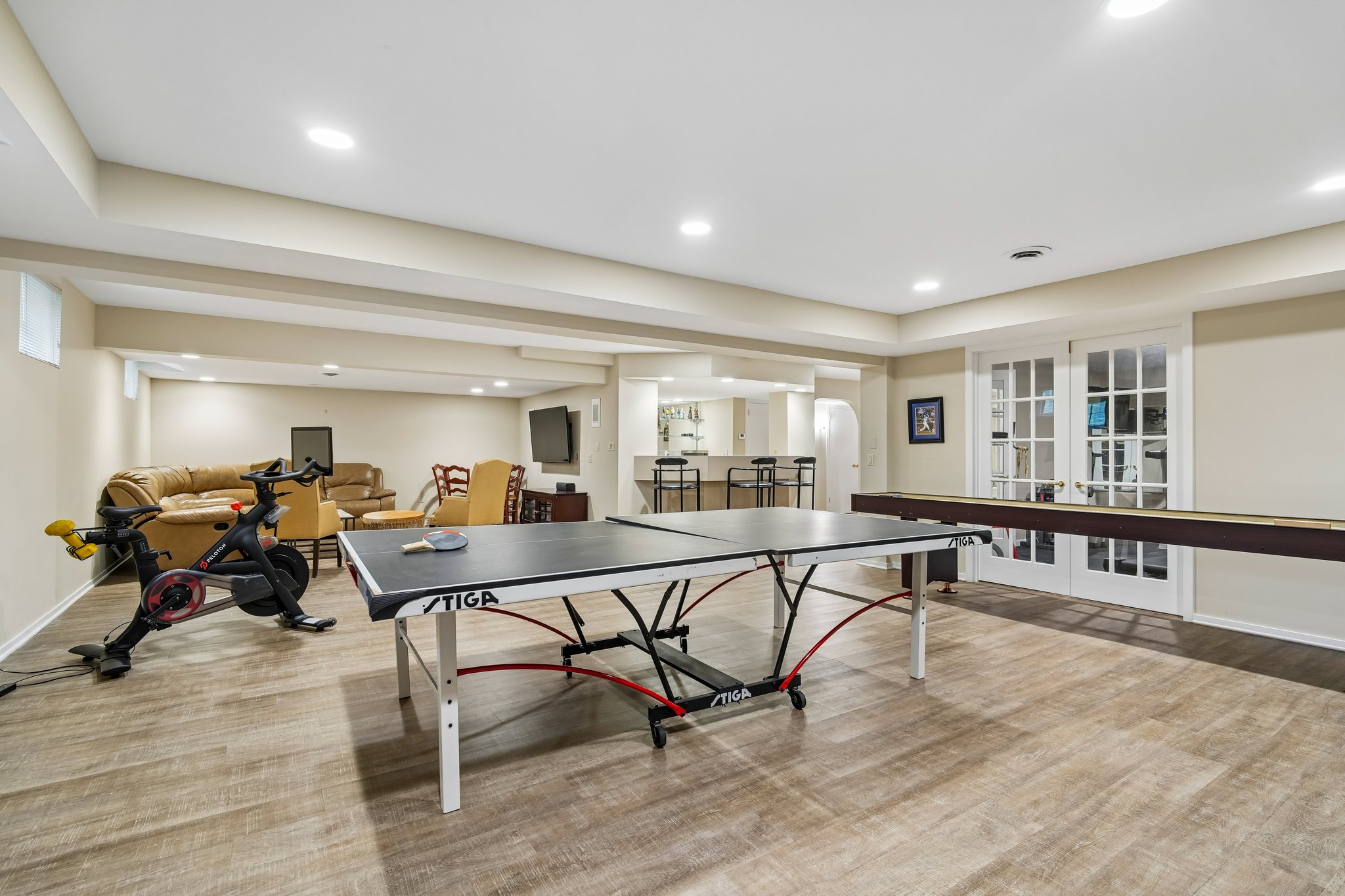 Another view of spacious lower level that shows french glass doors to the fitness room.