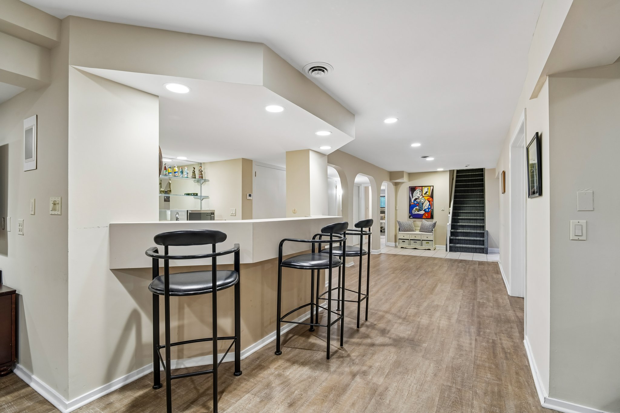 Stylish bar with dedicated seating connects to the lower-level kitchenette, creating a premier entertainment hub. An ideal layout for hosting, offering a seamless flow between refreshments and recreation area.
