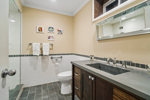 A masterfully coordinated full bath serving the lower level suite. Featuring a beautiful subway tile surrounded with custom gray border, perfectly matched to the tile floor and designer countertop for a sleek, cohesive look.
