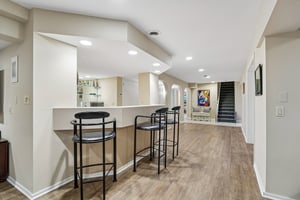 Stylish bar with dedicated seating connects to the lower-level kitchenette, creating a premier entertainment hub. An ideal layout for hosting, offering a seamless flow between refreshments and recreation area.