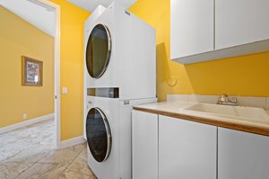 Laundry room with full size stacked washer/dryer & plenty of storage cabinets on both sides of washer/dryer.