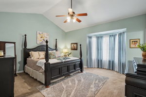 Main floor Primary Suite with vaulted ceilings and bay window.