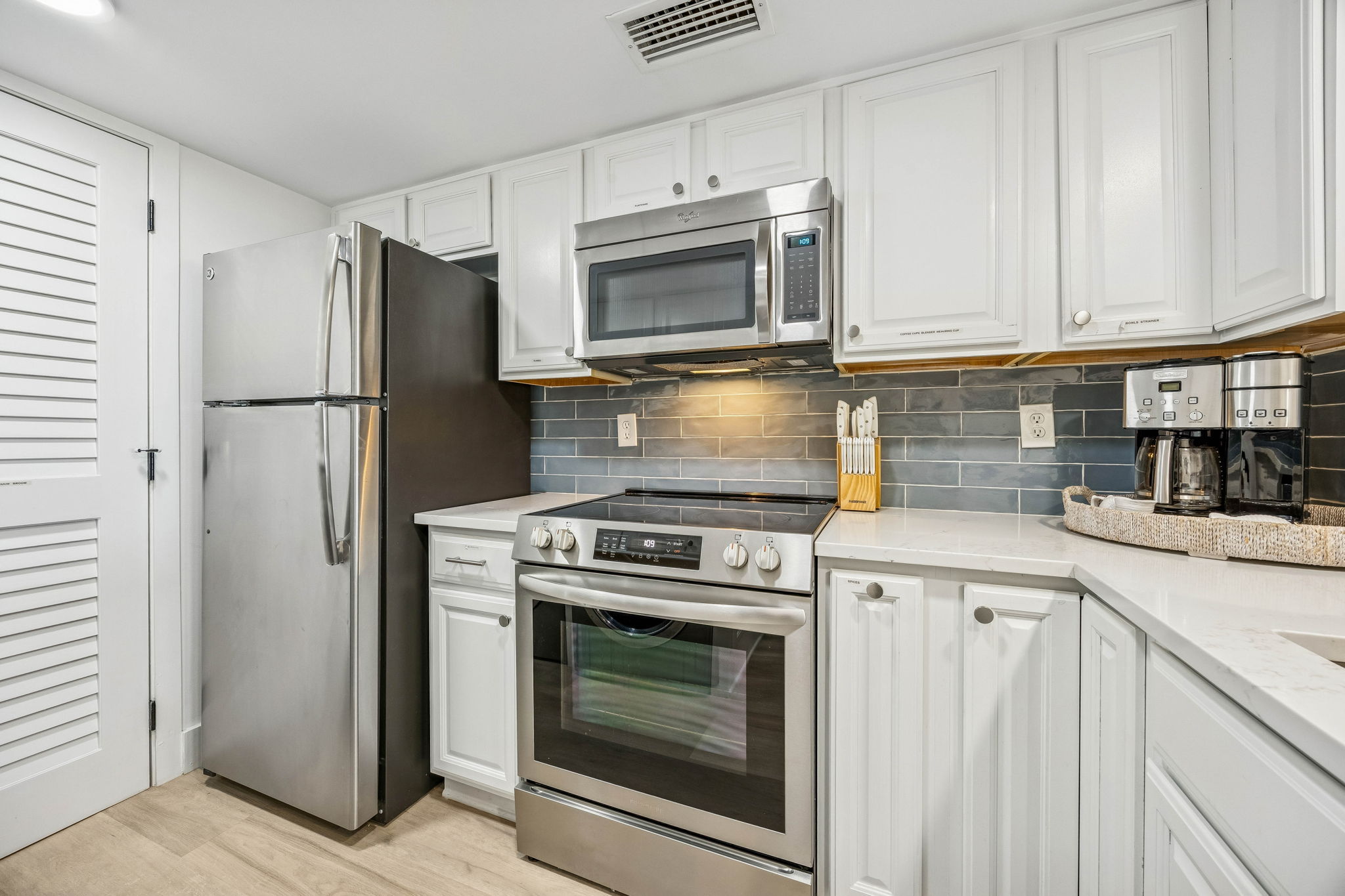 The kitchen continues the updated coastal look with quartz counters, stainless appliances, and a crisp, clean palette ...