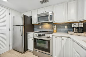 The kitchen continues the updated coastal look with quartz counters, stainless appliances, and a crisp, clean palette ...