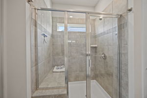 Shower in luxury! Large tiled shower with glass tile listel, clerestory window for natural light and seating.  Custom stainless towel/robe hooks already installed.
