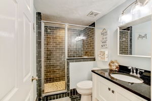 ... with a sleek walk-in shower of subway tile, paired with a modern vanity and fixtures.