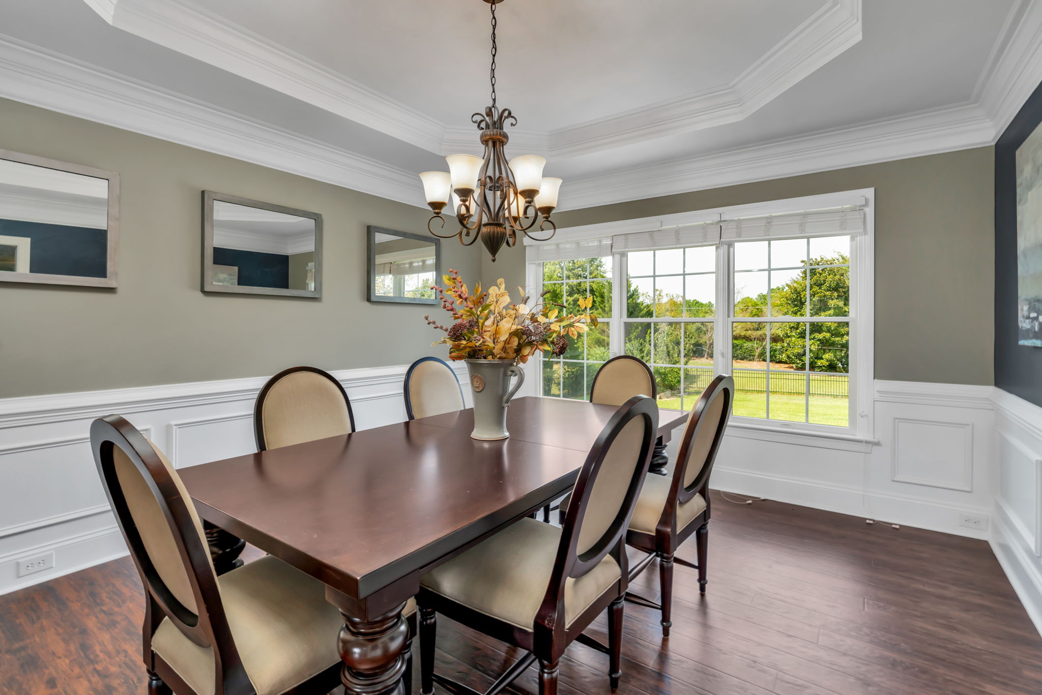 Elegant dining room with heavy crown molding, tray ceilings, chair rail and shadow box wainscoting.