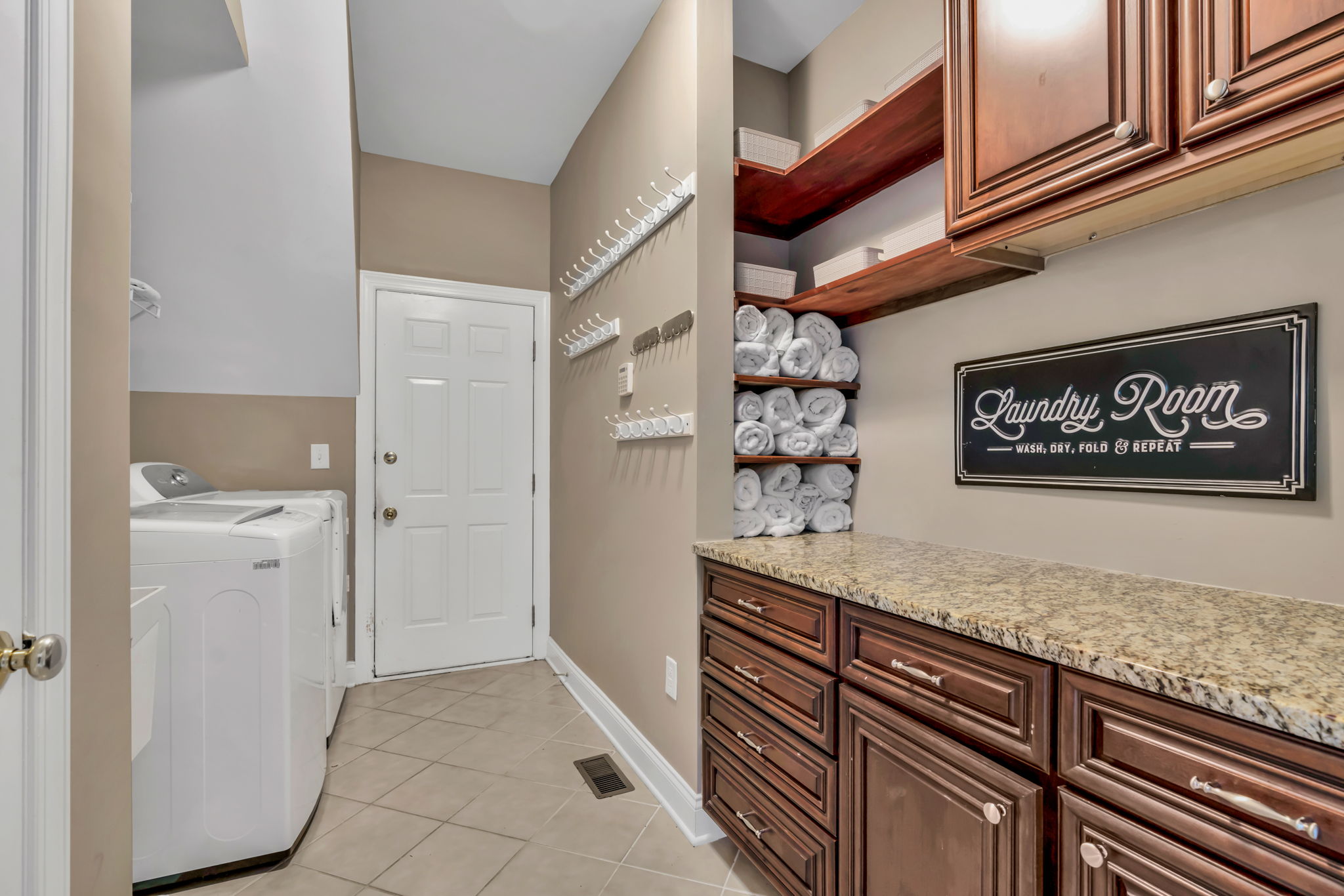 Large laundry room and mud room with built-in cabinets, shelves, tub sink and granite countertop.