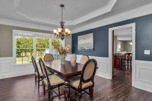 Elegant dining room with heavy crown molding, tray ceilings, chair rail and shadow box wainscoting.