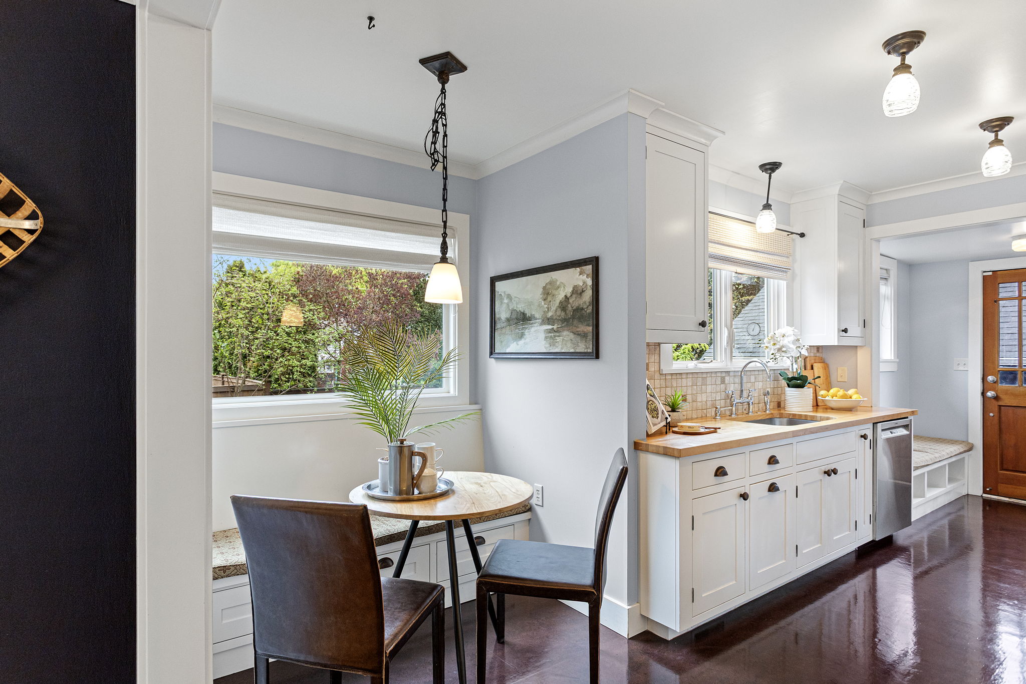 The eating nook tucks in beside the sink — built-in bench, pendant light, east-facing window. Practical and considered in equal measure.