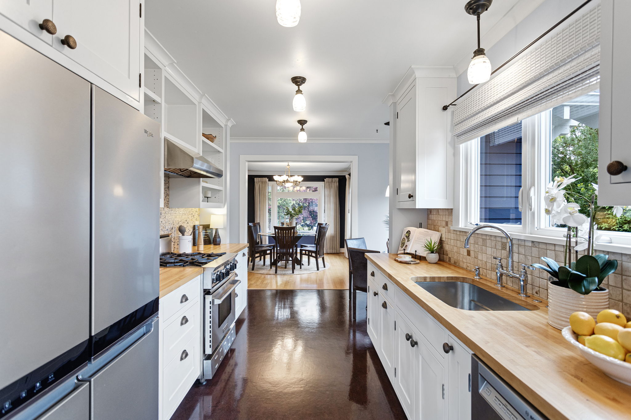 Looking back toward the dining room — the kitchen stays connected to the party. Marmoleum underfoot, cased opening straight ahead.