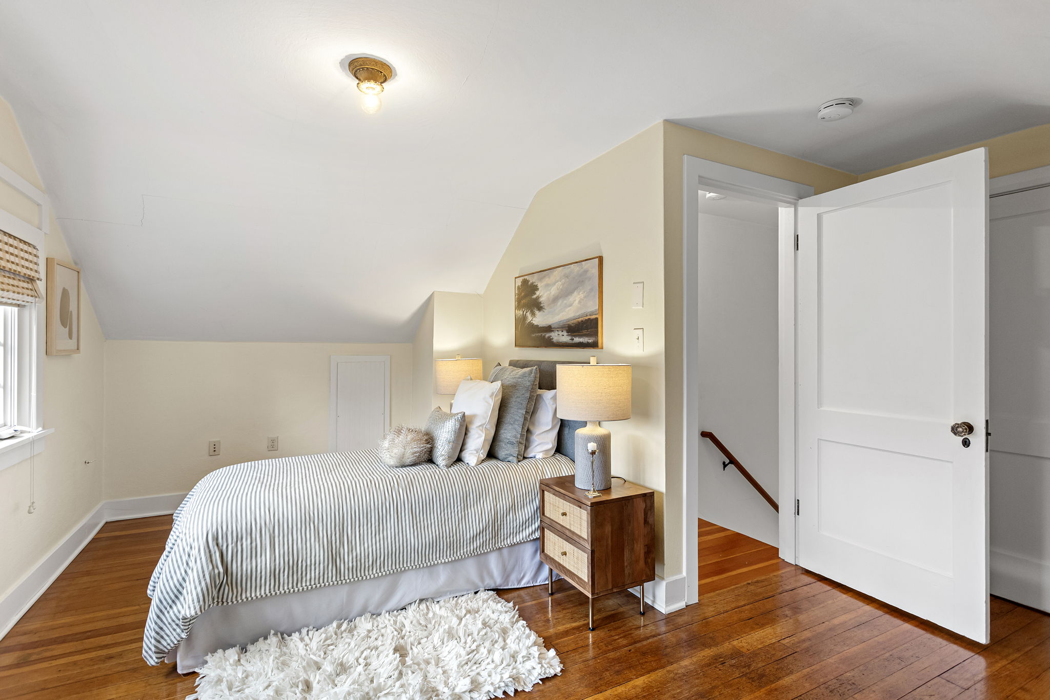 L-shaped, with the walk-in closet behind those two white doors. The roofline takes some of the ceiling — the floor plan gives it back.