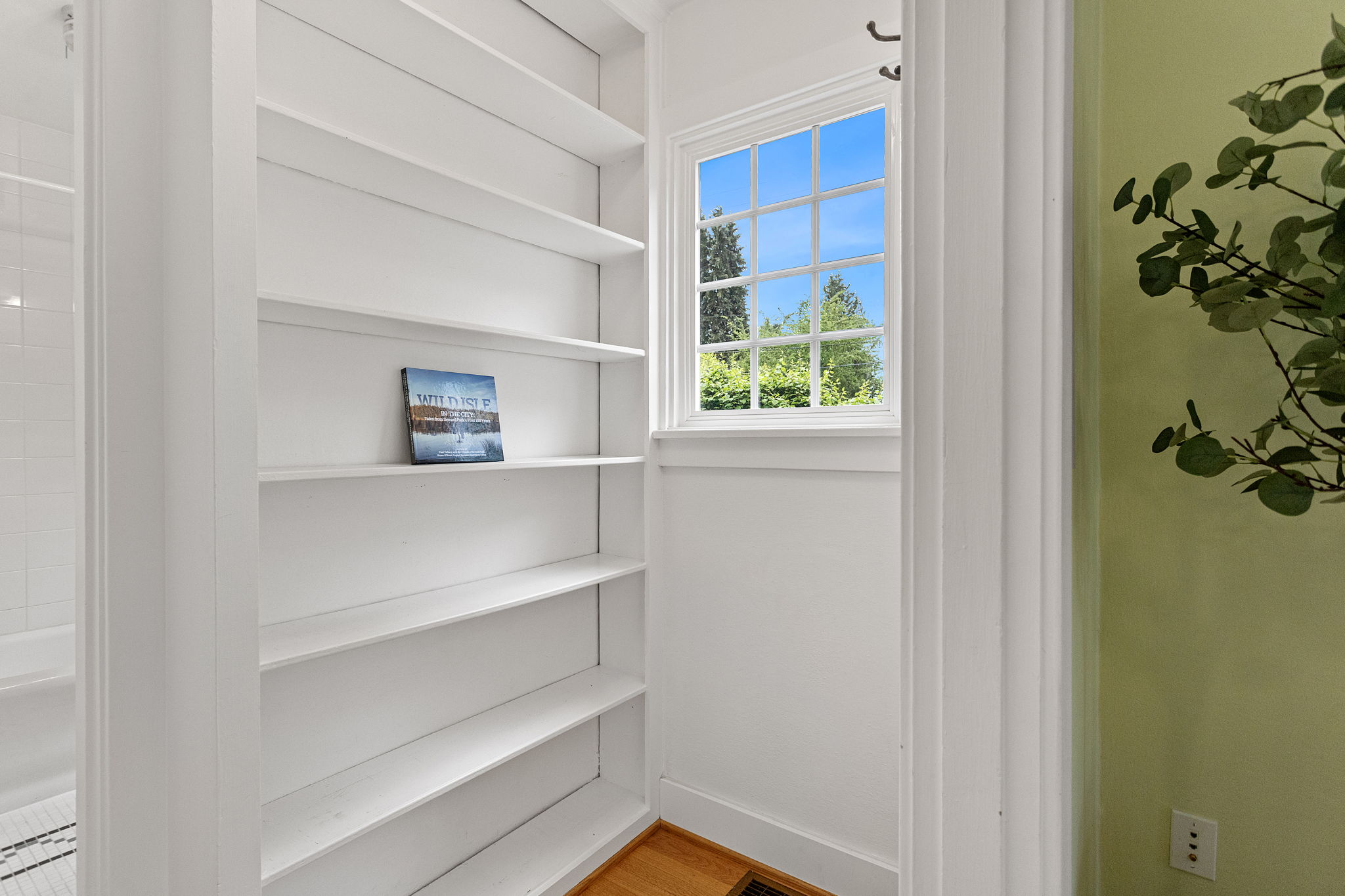 Built-in bookcase, stair landing, blue sky in the window. A pause before the Craftsman stops being modest.