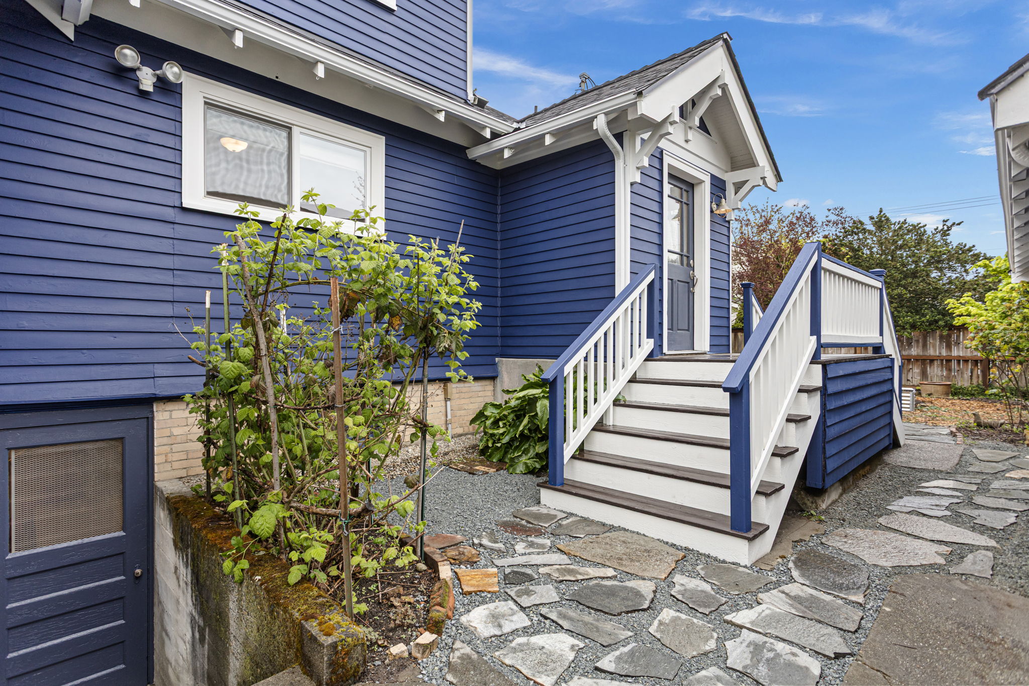 Off the kitchen, the split staircase drops you east to the garden or west toward the driveway and garage. New flagstone, exterior basement access just left of the stairs.